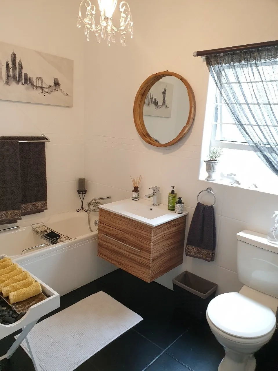 A refreshed bathroom with painted tiles, a floating timber vanity and a round mirror.