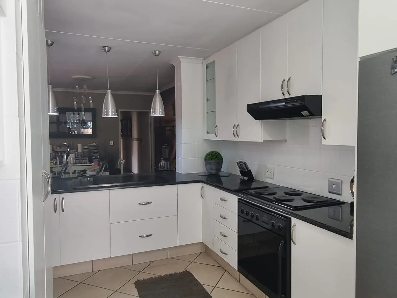 After: the kitchen with white cabinets and white wall tiles against black countertops and a black oven.