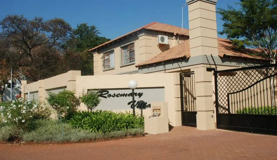 After: the entrance to the complex with smooth cream walls, a grey name panel, black gates and a planted garden bed.