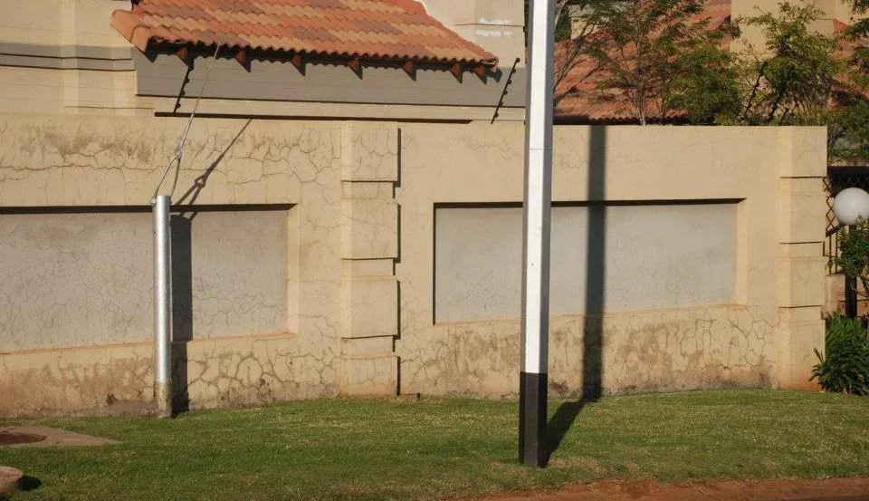 Before: a close view of a cream boundary wall with cracked, weathered paint and grey recessed panels.