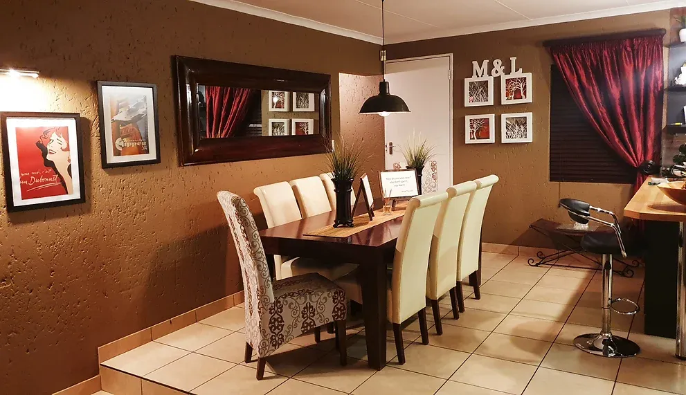 After: the dining room with caramel-brown walls, a dark table with cream high-backed chairs, a large mirror and framed prints.
